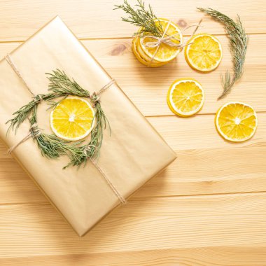 Güzel, yuvarlak, turuncu dilimler ve hediye paketi. Arka plandaki tahta masa. Üst Manzara. Noel dekorasyonu kavramı, çevre dostu ambalaj, tatlı malzemeleri, kendin yap..