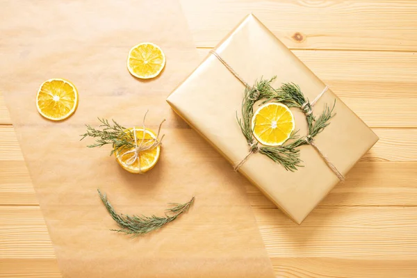 Beautiful round dry orange slices with gift box on baking paper. Wooden table on the background. Top view. Concept of funny face from food, Christmas decor, ingredients for desserts, do it yourself.
