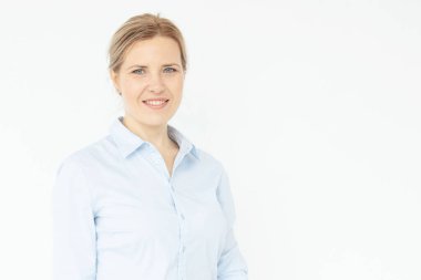 Beyaz duvar arkasında poz veren kendinden emin genç bir kadının portresi. Mavi gözlü mutlu sarışın kız. Mavi gömlek. Doğal güzellik, kadın cinselliği, iş saç stili konsepti. Boşluğu kopyala