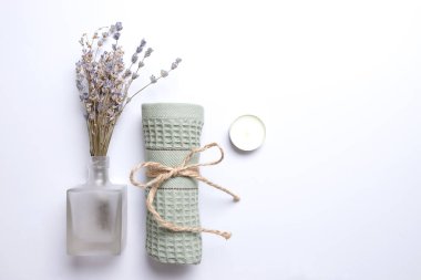 Spa salonu, banyo dekorasyonu, rahat ev, kadınsı. Cam bir şişede doğal kuru lavanta çiçekleri, sarılıp sarmalanmış havlu, mum manzaralı. Uzayı kopyala Beyaz arkaplan.