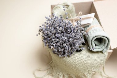Pamuk havlu, güzel, kuru lavanta buketi, kahverengi bir kutuda hediye. Organik kişisel bakım kutusu, el işi hediye paketi, spa, banyo dekoru, aroma, konforlu ev konsepti. Hiç kimse. Uzayı kopyala Bej arkaplan