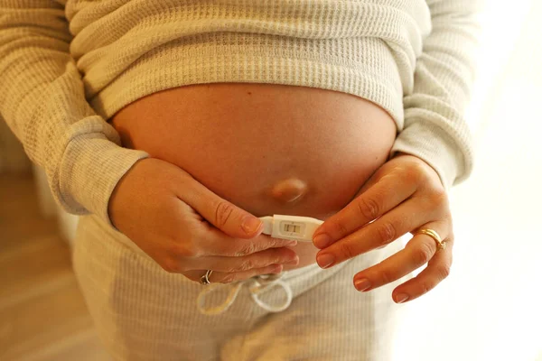 Hamile Bir Kadın Karnının Önünde Iki Tane Hamilelik Testi Tutuyor — Stok fotoğraf