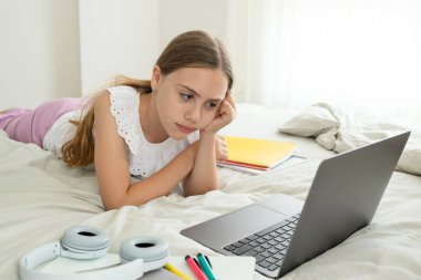 Liseli kız bilgisayar ekranının önünde ders çalışırken kafasını tutuyor. Mutsuz 10 yaşındaki kız tedirgin, ödev hazırlıyor, sınav yapıyor. Çocukların öğrenim, eğitim ve çevrimiçi sorunları kavramı.