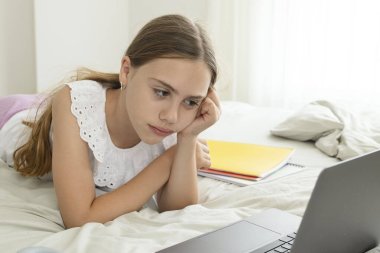 Liseli kız bilgisayar ekranının önünde ders çalışırken kafasını tutuyor. Mutsuz 10 yaşındaki kız tedirgin, ödev hazırlıyor, sınav yapıyor. Çocukların öğrenim, eğitim ve çevrimiçi sorunları kavramı.