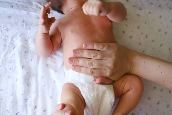 妈妈的手按摩一个患感冒的新生儿的腹部 妈妈轻轻地按摩她1 2个月大的孩子的腹部 免版税图库照片