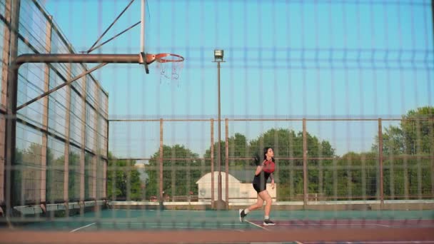 プロの裁判所で日没するバスケットボール選手がボールで走り ボールをバスケットボールフープに投げ込む ハンドヘルドシューティング — ストック動画