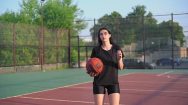 Beyaz kız basketbolcu dışarıda atış talimi yapıyor..