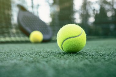 Tenis raketleri ve topları suni çimlerin üzerine koyun.
