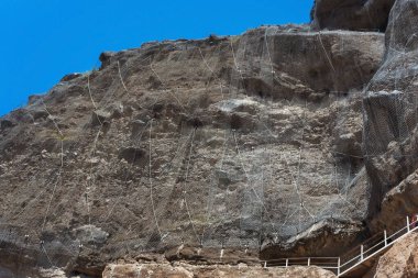 Dağlarda bir kayanın üzerindeki metal ağ. Dağdaki kaya düşüşüne karşı koruma inşaatı.