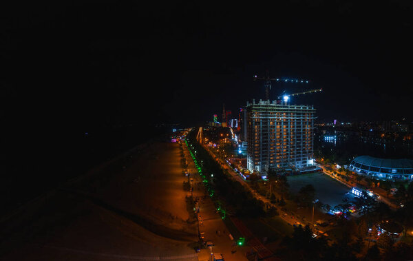 Строительство здания на побережье Черного моря в Батуми в Грузии. Набережная и пляж в Батуми ночью вид с воздуха