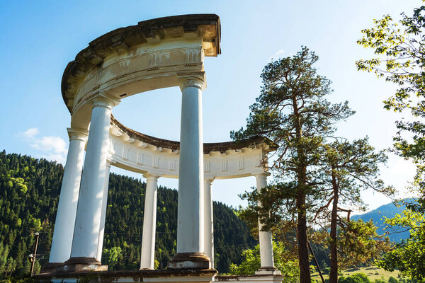 The old rotunda in the mountains of the resort town of Borjomi in Georgia. Gazebo made of gypsum columns in the mountain forest in summer
