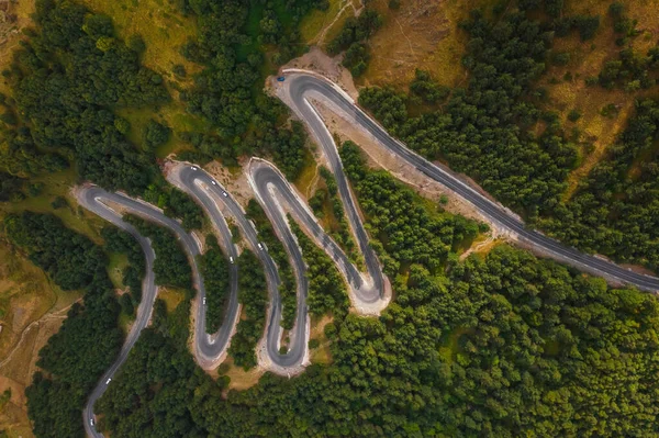 ジョージア州のKazbei山のGergetiトリニティ教会の近くの急な蛇紋岩の道の空中ビュー 玉座からの緑の森の景色の間の山道 — ストック写真