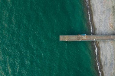 Yukarıdan deniz manzaralı boş iskele. Gürcistan 'da Karadeniz' de Batumi 'de bir çakıl taşı kumsalındaki iskele bir insansız hava aracından.