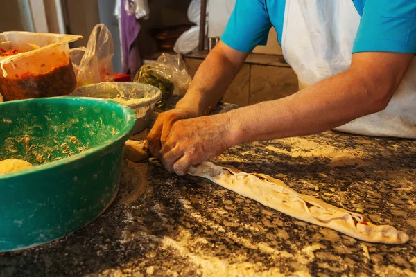 Cooking a closed pie pide in Turkey. Traditional Turkish unsweetened pie. Male chef cooks pie pizza hands close up