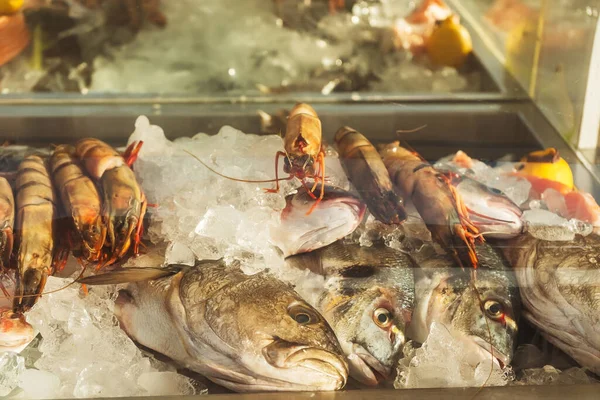 冷蔵庫の窓の氷の上に大きなエビや魚 カフェレストランでのシーフードから選択します 新鮮な裸の王のエビ — ストック写真