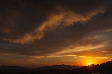 Türkiye 'deki dağlarda gün batımında güzel, ateşli bir gökyüzü. Batan güneşe karşı bulutların dokusu