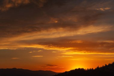 Türkiye 'deki dağlarda gün batımında güzel, ateşli bir gökyüzü. Batan güneşe karşı bulutların dokusu