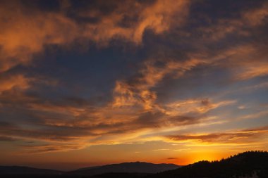 Türkiye 'deki dağlarda gün batımında güzel, ateşli bir gökyüzü. Batan güneşe karşı bulutların dokusu