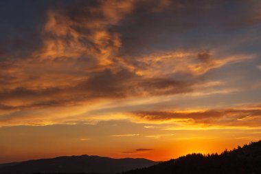 Türkiye 'deki dağlarda gün batımında güzel, ateşli bir gökyüzü. Batan güneşe karşı bulutların dokusu