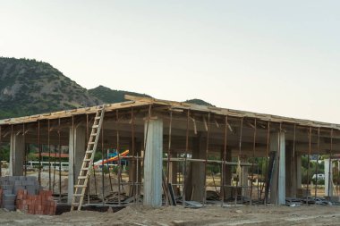 Dağların arka planına karşı Türkiye 'de bir ev inşaatı. Güçlendirilmiş beton bir binanın ereksiyonu. Formwork Prop Desteklemek için Ayarlanabilir Çelik Tüpü Desteği