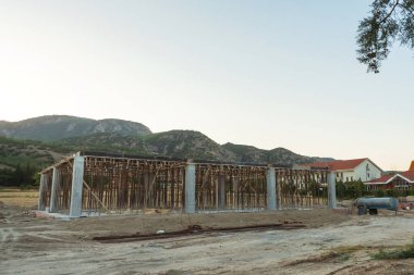 Dağların arka planına karşı Türkiye 'de bir ev inşaatı. Güçlendirilmiş beton bir binanın ereksiyonu. Formwork Prop Desteklemek için Ayarlanabilir Çelik Tüpü Desteği