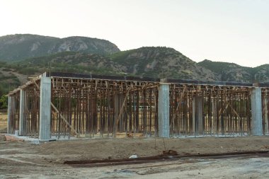 Dağların arka planına karşı Türkiye 'de bir ev inşaatı. Güçlendirilmiş beton bir binanın ereksiyonu. Formwork Prop Desteklemek için Ayarlanabilir Çelik Tüpü Desteği