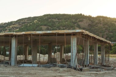 Dağların arka planına karşı Türkiye 'de bir ev inşaatı. Güçlendirilmiş beton bir binanın ereksiyonu. Formwork Prop Desteklemek için Ayarlanabilir Çelik Tüpü Desteği