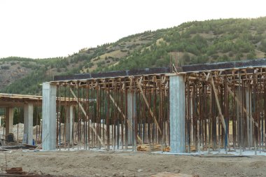 Dağların arka planına karşı Türkiye 'de bir ev inşaatı. Güçlendirilmiş beton bir binanın ereksiyonu. Formwork Prop Desteklemek için Ayarlanabilir Çelik Tüpü Desteği