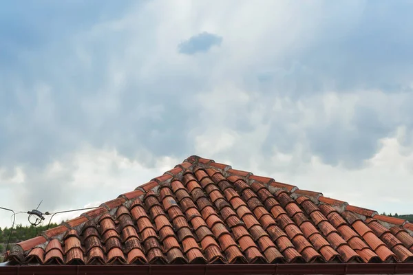 Red tiles on the roofs of houses in Turkey in the village. Tiled roofs against the sky with clouds