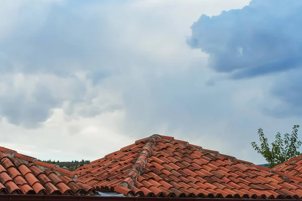 Red tiles on the roofs of houses in Turkey in the village. Tiled roofs against the sky with clouds