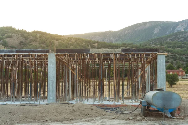 Dağların arka planına karşı Türkiye 'de bir ev inşaatı. Güçlendirilmiş beton bir binanın ereksiyonu. Formwork Prop Desteklemek için Ayarlanabilir Çelik Tüpü Desteği