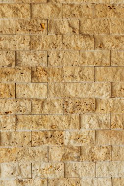 marble texture of small yellow squares. rough processing of travertine on the wall. rough stone wall