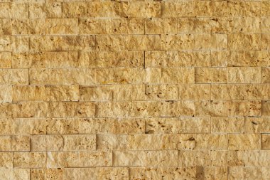 marble texture of small yellow squares. rough processing of travertine on the wall. rough stone wall