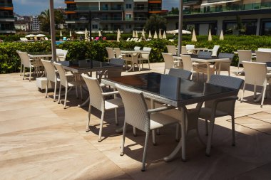 table with chairs by the pool in a tourist place. place to consume food in the hotel. rattan chair next to glass top table