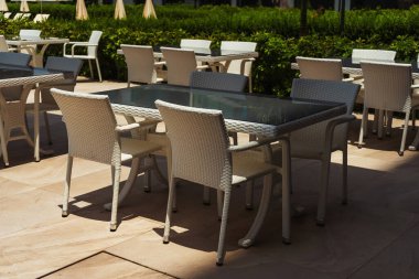 table with chairs by the pool in a tourist place. place to consume food in the hotel. rattan chair next to glass top table