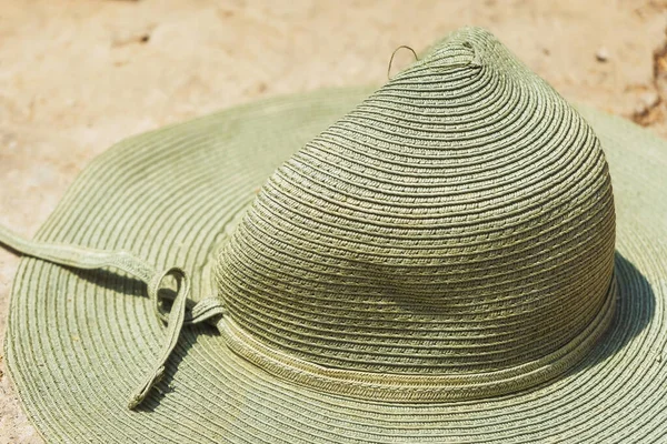 Green women\'s hat on a stone. Forgotten hat in a tourist place.