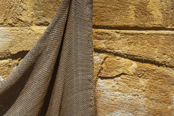 Old burlap on the wall in the interior. old hanging bag on the street. Dirty cloth on the wall of the house