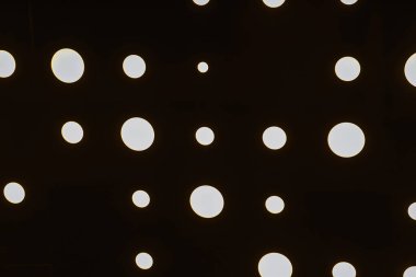 aluminum sheet with holes and light at the back. dark texture with round slits. corrugated metal sheet in the interior with lighting