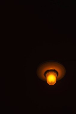 Night lantern on a dark street. The yellow incandescent lamp illuminates the darkness.
