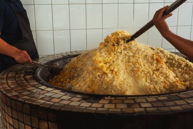 mixing rice in plov center of tashkent. cooking pilaf in uzbekistan. mixing pilaf in a cast iron cauldron for tourists