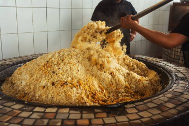 mixing rice in plov center of tashkent. cooking pilaf in uzbekistan. mixing pilaf in a cast iron cauldron for tourists