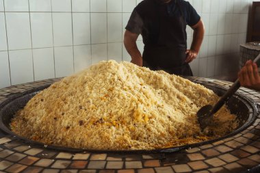mixing rice in plov center of tashkent. cooking pilaf in uzbekistan. mixing pilaf in a cast iron cauldron for tourists