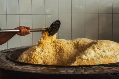 mixing rice in plov center of tashkent. cooking pilaf in uzbekistan. mixing pilaf in a cast iron cauldron for tourists