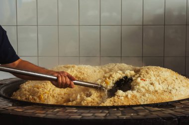 mixing rice in plov center of tashkent. cooking pilaf in uzbekistan. mixing pilaf in a cast iron cauldron for tourists