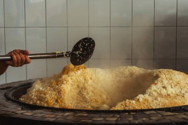 mixing rice in plov center of tashkent. cooking pilaf in uzbekistan. mixing pilaf in a cast iron cauldron for tourists