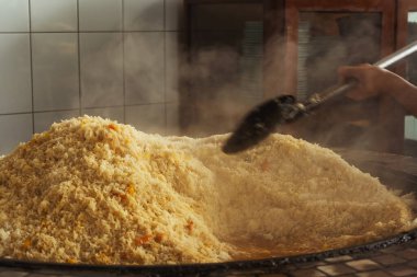 mixing rice in plov center of tashkent. cooking pilaf in uzbekistan. mixing pilaf in a cast iron cauldron for tourists
