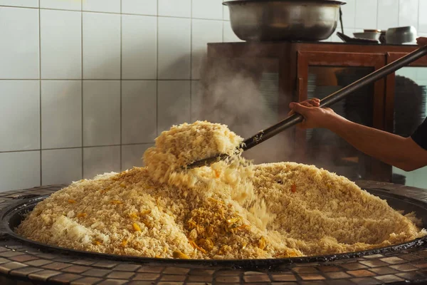 mixing rice in plov center of tashkent. cooking pilaf in uzbekistan. mixing pilaf in a cast iron cauldron for tourists