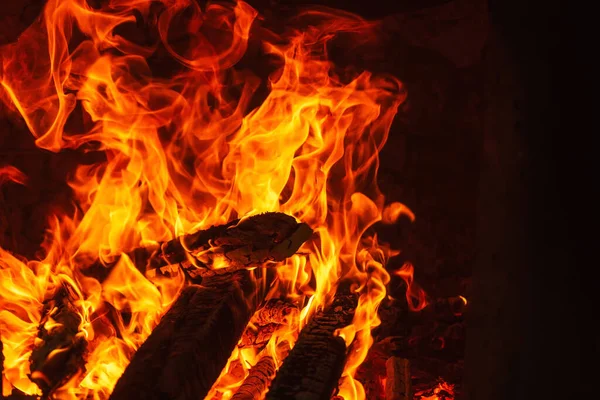 Big fire in the Uzbek oven for cooking pilaf. orange fire on a dark background in a brick oven. fire for cooking