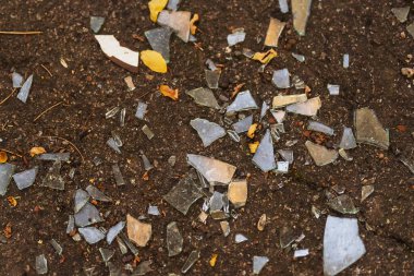 shards of glass on clay ground. small pieces of broken windows. texture of pieces of glass on the floor