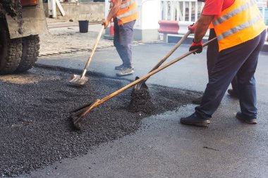 men lay fresh bitumen on the road. laying a new road in Georgia. hot asphalt poured out of a truck